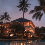 Home Luxurious tropical resort with swimming pool and palms at dusk, perfect for a tranquil vacation.